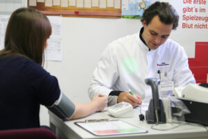 Foto: Ein Arzt und Spenderin bei der Anamnese vor einer Blutspende.